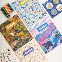 A collection of nature-themed activity boxes with various colorful journals, badges, sticker sheets, and colored pencils displayed on a white background.