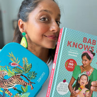 Kids lunch box with animal print design held by parent with cookbook