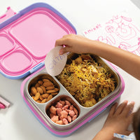 Child's hands placing a 'carbs' label on a divided lunch container with snacks.