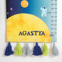 Personalized growth chart with colorful tassels and 'AGASTYA' text .