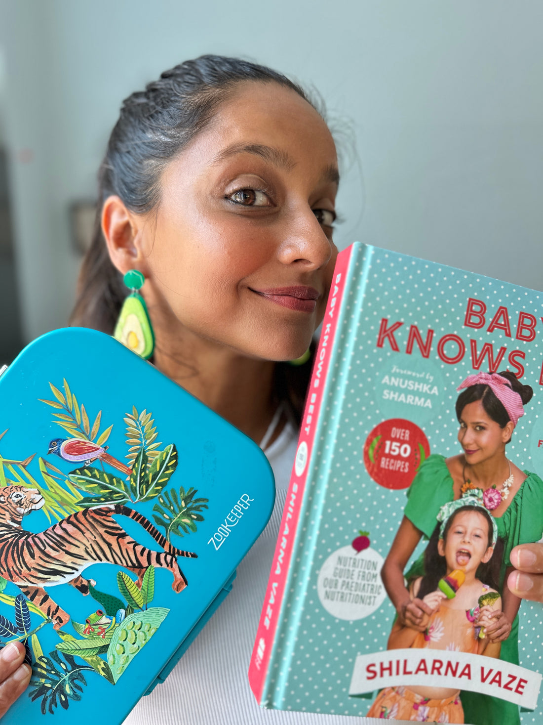 Kids lunch box with animal print design held by parent with cookbook 