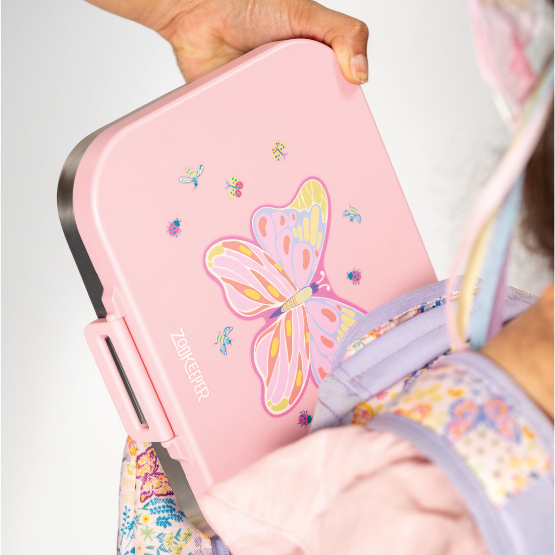Pink bento box with butterfly design held by a person